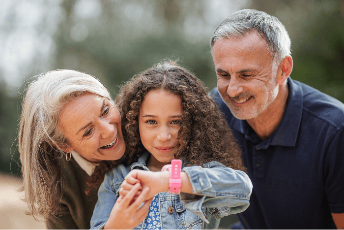 Girl using an Xplora smartwatch with grandparents