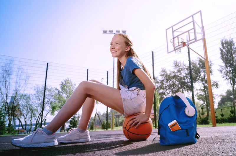 Girl on outside basketball court with Xplora Teen filter phone